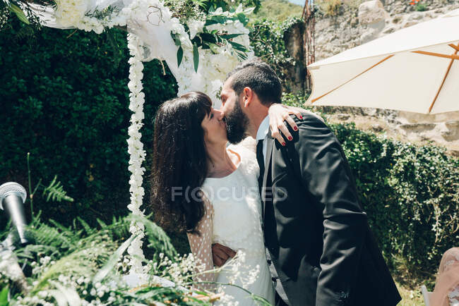Joven novia y novio besándose en la ceremonia de boda - foto de stock