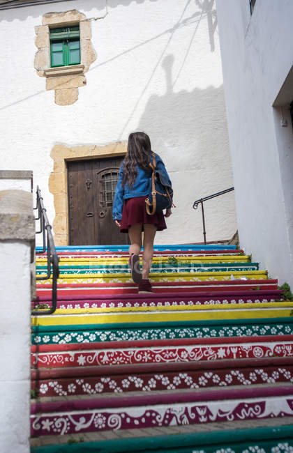 Girl walking up on colorful patterned stairs in town — Stock Photo