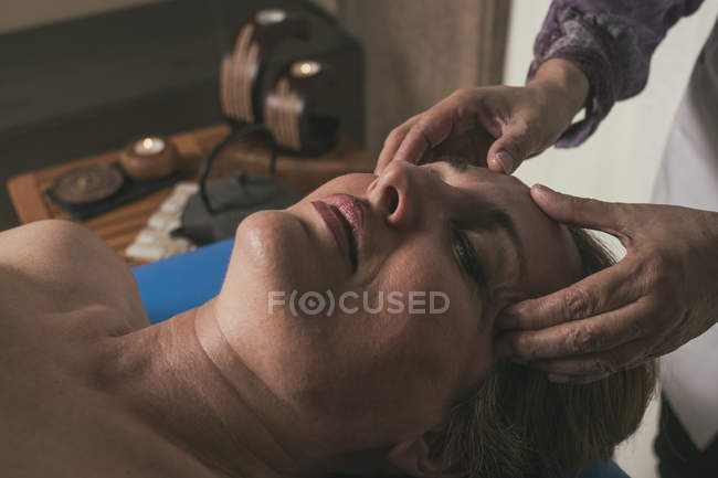 Terapeuta masajeando la cabeza femenina en sala de masajes - foto de stock