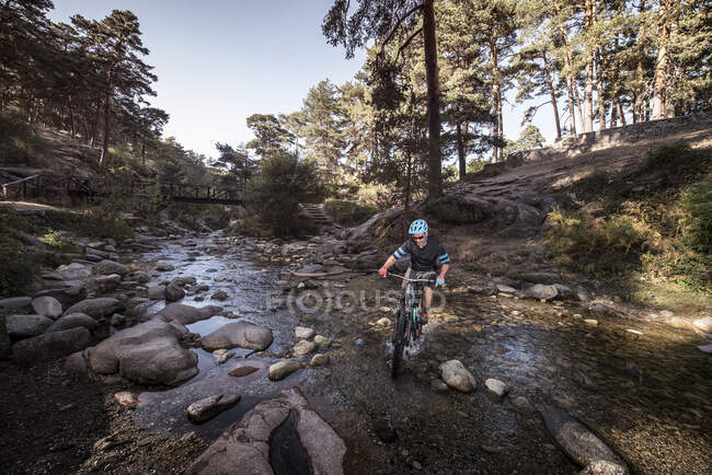 Biker riding a bike over a river — Stock Photo