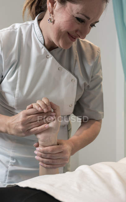 Terapeuta masajeando mano femenina en sala de masajes - foto de stock