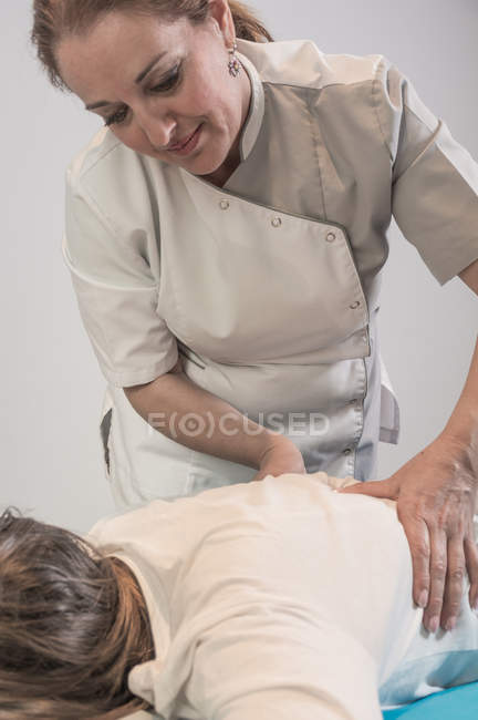 Terapeuta massageando feminino de volta à mesa na sala de massagem — Fotografia de Stock