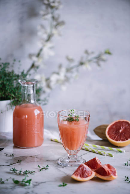 Fresh grapefruit juice in glass and bottle on white marble tabletop — Stock Photo