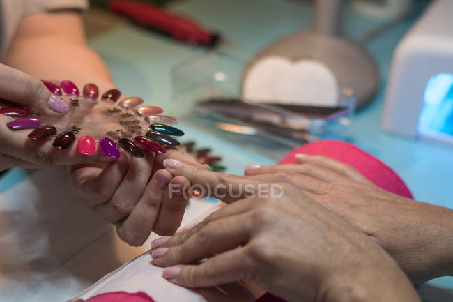 Manicure femminile mostrando tavolozza smalto al cliente nel salone di bellezza — Foto stock