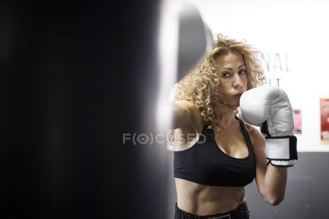 Grave allenamento femminile in palestra con sacco da boxe — Foto stock