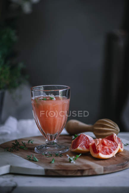 Zumo de pomelo fresco en vidrio sobre tabla de madera con ingrediente - foto de stock