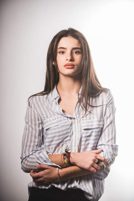 Молода жінка в смугастій сорочці позує на сірому фоні — стокове фото