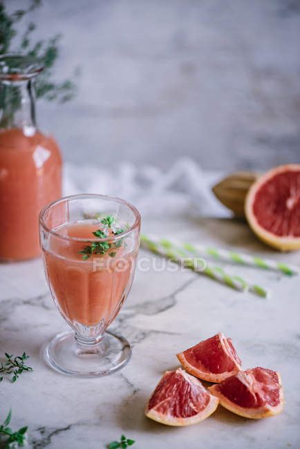 Свіжий грейпфрутовий сік у склянці з інгредієнтом на кухонному столі — стокове фото