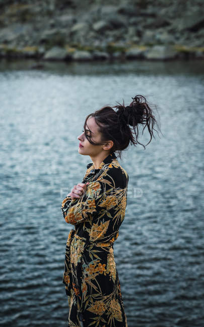Молода жінка стоїть на самоті на березі озера з блакитною водою — стокове фото