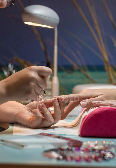 Female manicurist painting nails of client in beauty salon — Stock Photo