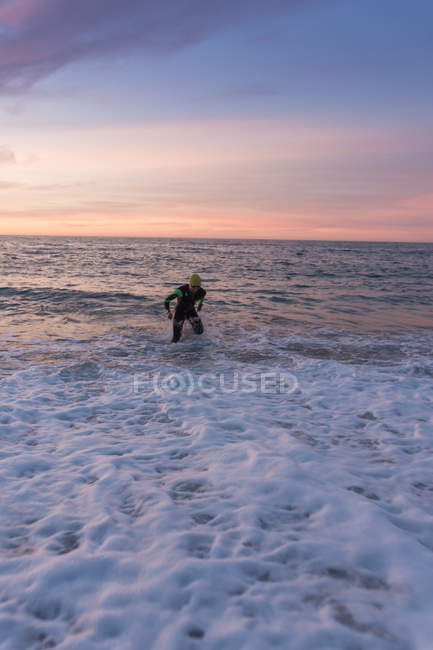 Entrenamiento seguro de triatleta en el mar al atardecer - foto de stock