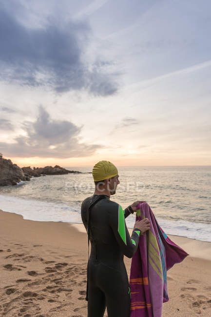 Triatleta de pie en la playa de arena - foto de stock