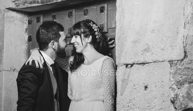 Молодая невеста и жених стоят рядом со стеной — стоковое фото