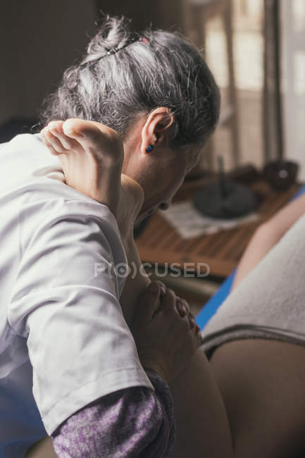Terapeuta haciendo masaje de reflexología del pie en paciente femenino - foto de stock