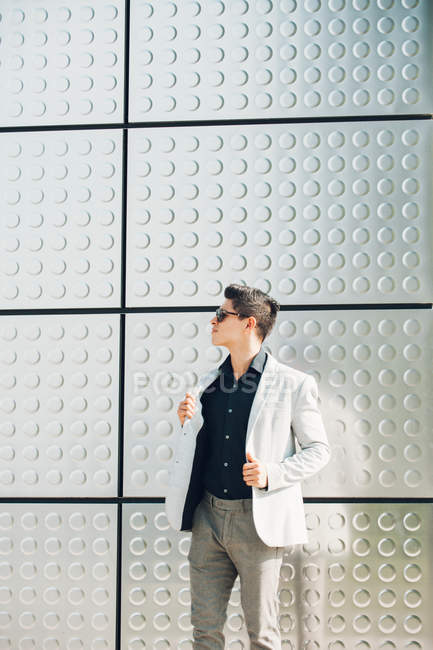 Young guy in elegant outfit standing near building wall — Stock Photo