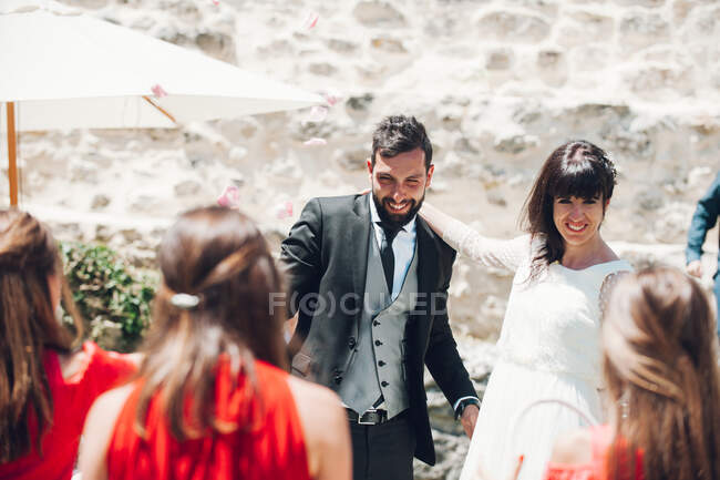 Young bride and groom walking under rose petals — Stock Photo