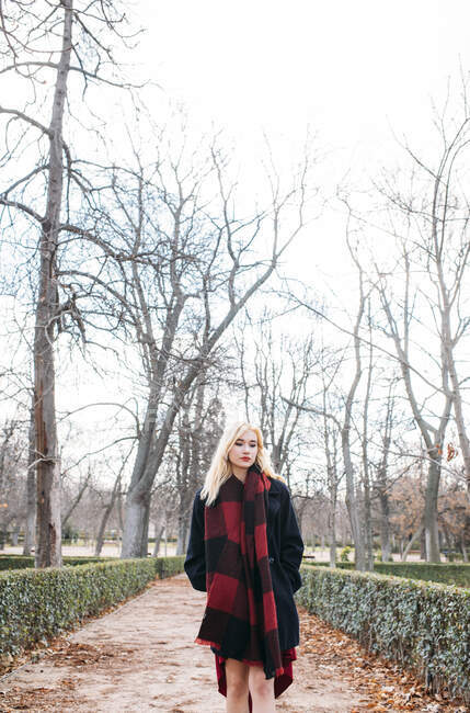 Jeune femme en robe rouge marchant dans le parc — Photo de stock