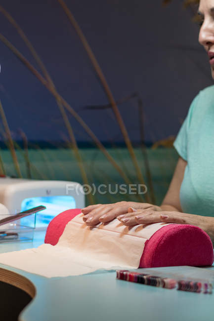 Mujer sentada en manicura en salón de belleza - foto de stock