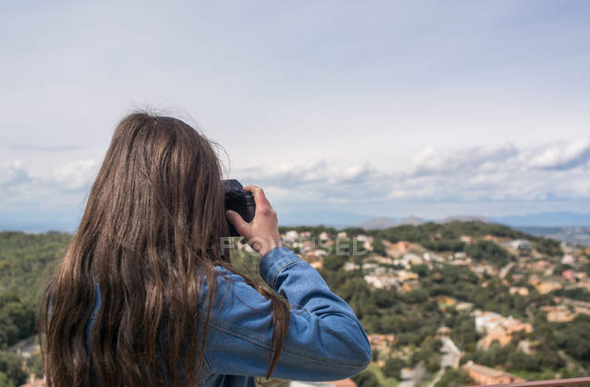 Female tourist taking photo of town from hill — Stock Photo