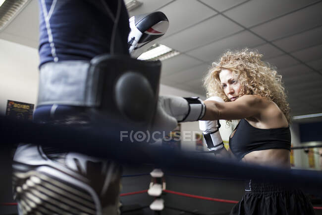 Взрослая женщина в боксёрских перчатках дерётся с партнером — стоковое фото