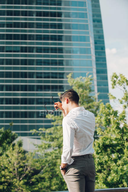 Ridendo giovane uomo d'affari in piedi contro grattacielo moderno — Foto stock