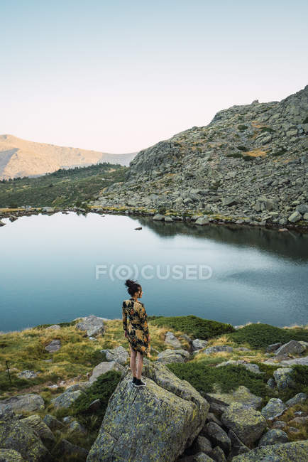 Жінка стоїть на скелях маленького озера в горах — стокове фото