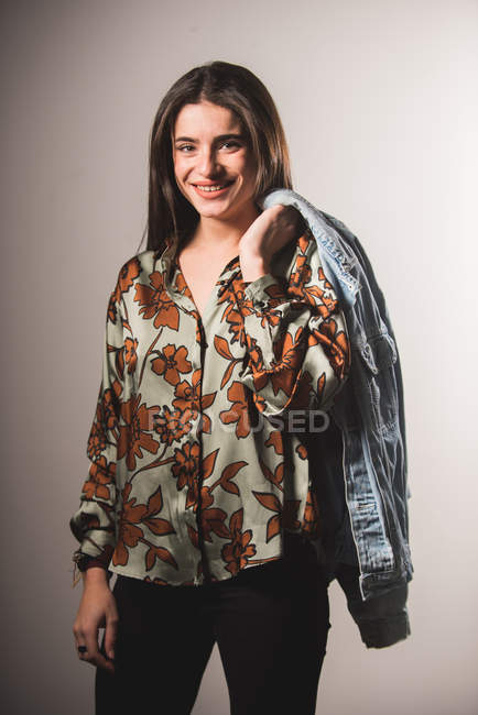 Chica sonriente en camisa estampada posando sobre fondo gris - foto de stock