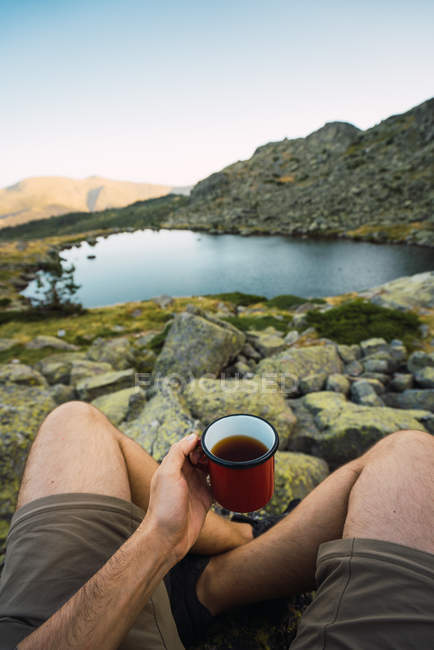 Cropped of man with mug in hand on shore of lake — Stock Photo