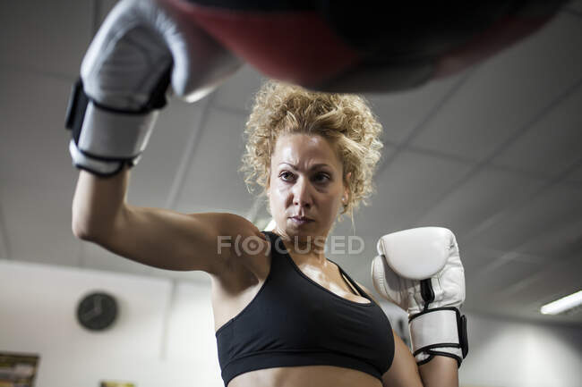 Sério treinamento da mulher no ginásio com saco de perfuração — Fotografia de Stock