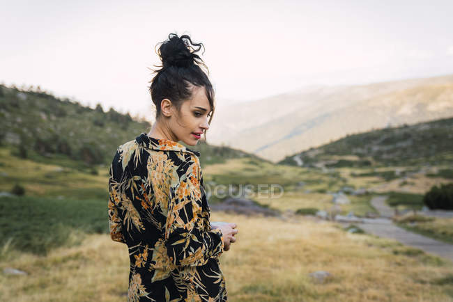 Femme décontractée en chemise colorée relaxante dans la vallée verdoyante des montagnes — Photo de stock