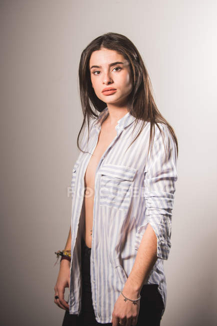 Sensual menina no listrado desabotoado camisa posando no cinza fundo — Fotografia de Stock