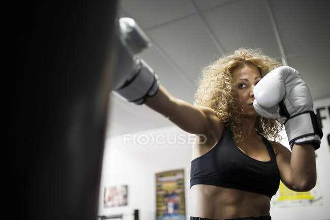 Серьезные женщины тренируются в тренажерном зале с боксерской грушей — стоковое фото