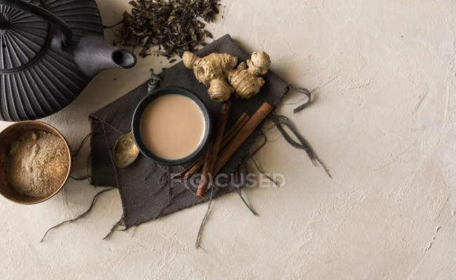 Tasse orientale de thé Chai au lait, cannelle, gingembre, poivre blanc et cardamome à la surface beige — Photo de stock
