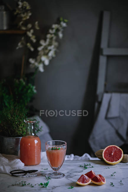 Suco de toranja fresco em vidro e garrafa em mesa de mármore branco — Fotografia de Stock