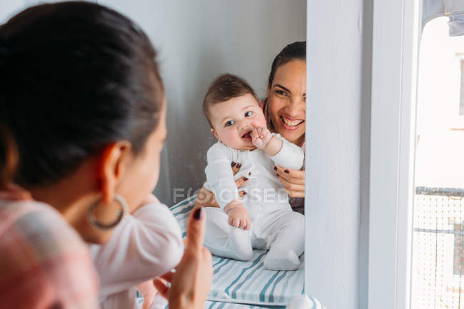 Sorridente madre che tiene in braccio divertente bambino in vivaio — Foto stock