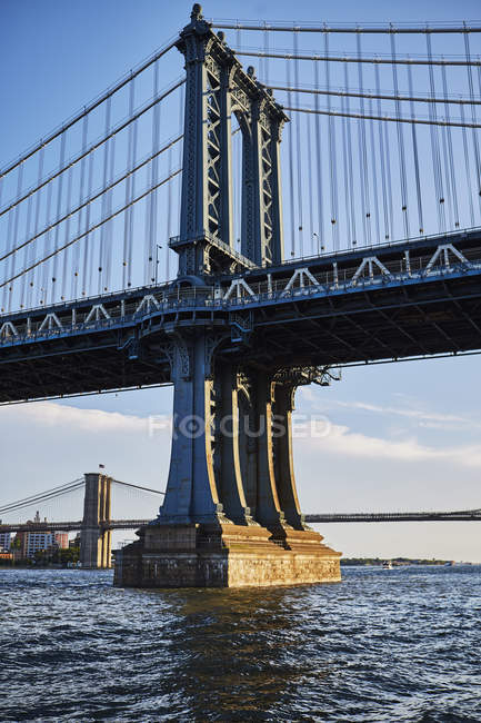 Manhattan Bridge over river on sunny day, Nueva York, Estados Unidos - foto de stock