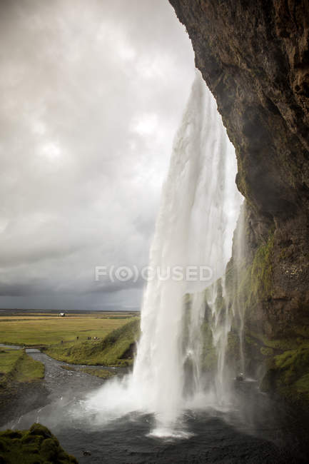 Cascada salpicando desde el acantilado de piedra, Islandia - foto de stock