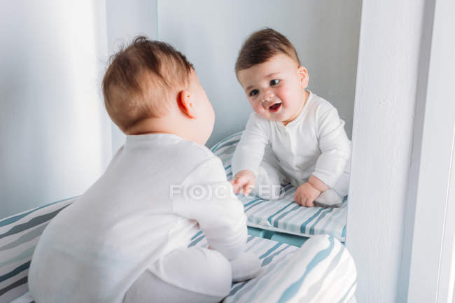 Menino brincalhão olhando para o espelho e fazendo rostos — Fotografia de Stock