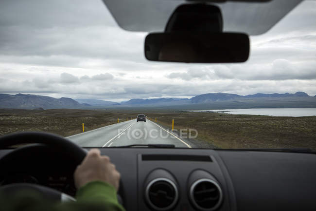 Mão humana no volante do automóvel na estrada na natureza, Islândia — Fotografia de Stock