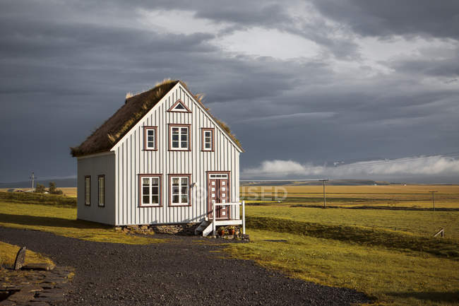 Maison de campagne avec toit en paille sous un ciel nuageux en Islande — Photo de stock