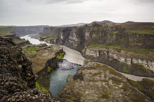 Pintoresco valle con acantilados rocosos y agua corriente en Islandia - foto de stock