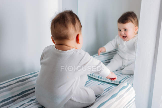 Menino doce espantado olhando para o espelho no berçário — Fotografia de Stock