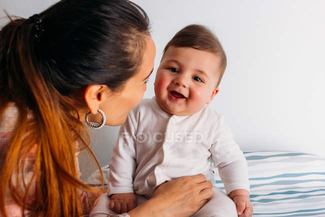 Lächelnde Mutter mit lustigem Baby im Kinderzimmer — Stockfoto