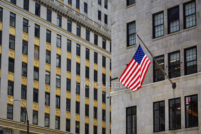 Bandera de EE.UU. colgando en la fachada de un edificio moderno en la calle de Nueva York, EE.UU. - foto de stock