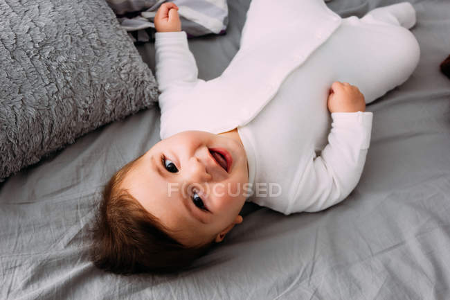 Portrait of laughing baby boy lying on bed — Stock Photo
