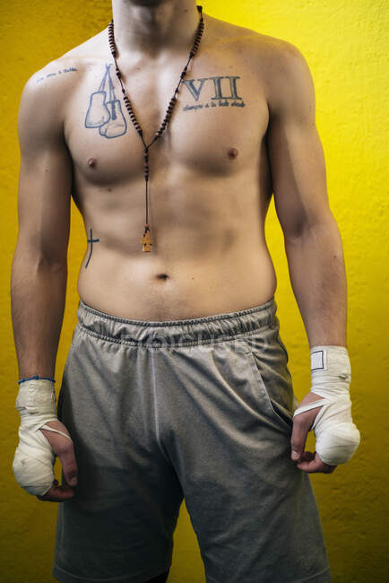 Впевнений м'язистий боєць стоїть з перев'язаними руками і дивиться геть . — стокове фото