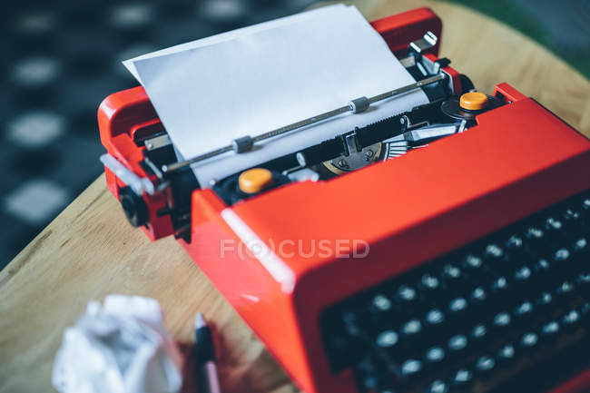 Nahaufnahme rote Schreibmaschine auf kleinem Tisch mit eingestecktem Papierblatt — Stockfoto