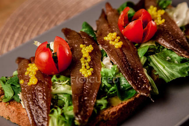 Крупним планом сендвіч з овочами і рибою на сірій тарілці — стокове фото