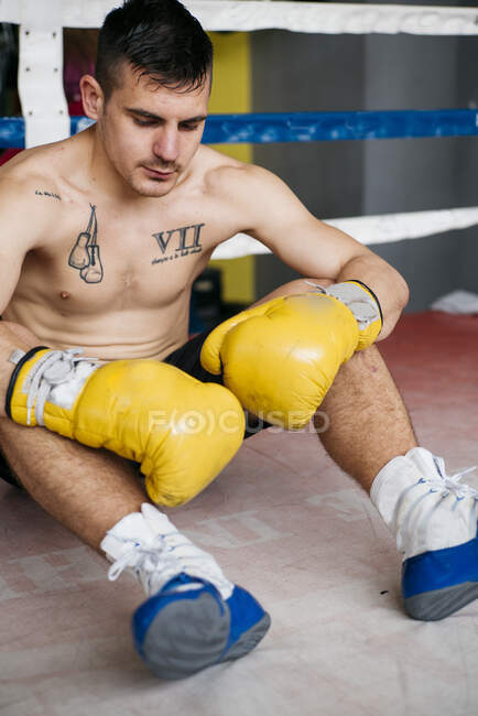 Без рубашки уверенный боксер в перчатках сидит на стуле на ринге. — стоковое фото