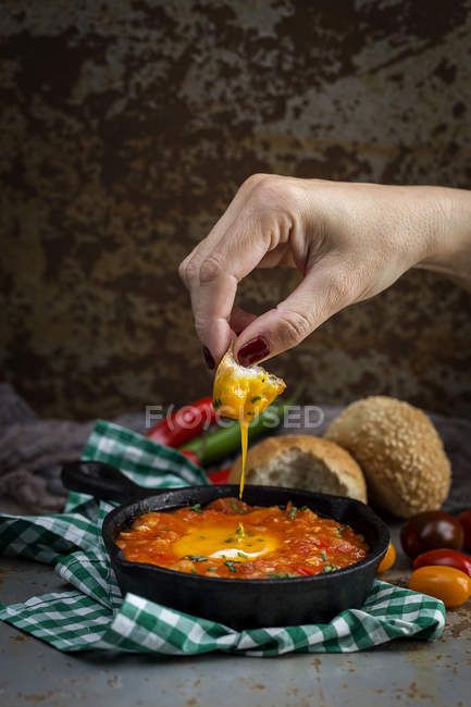 Mão humana sobre ovo frito com tomate, pimentas vermelhas e pão na frigideira — Fotografia de Stock